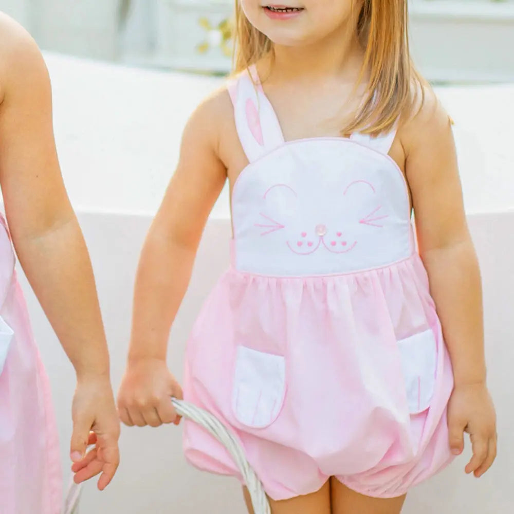 Child wearing a pink bunny-themed romper with a white top.
