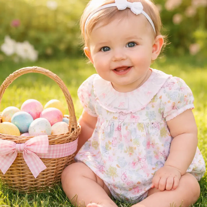 Baby sitting in grass with Easter eggs and basket
