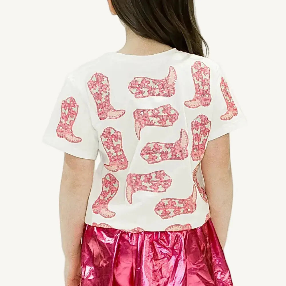 Child wearing a white t-shirt with pink boot designs and a pink skirt on a white background