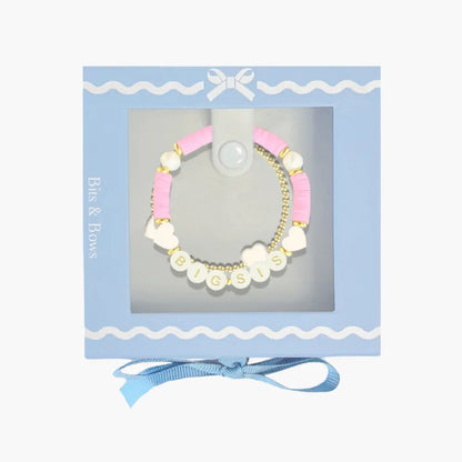 Bracelet with pink, white, and gold beads in a decorative box with a blue ribbon.
