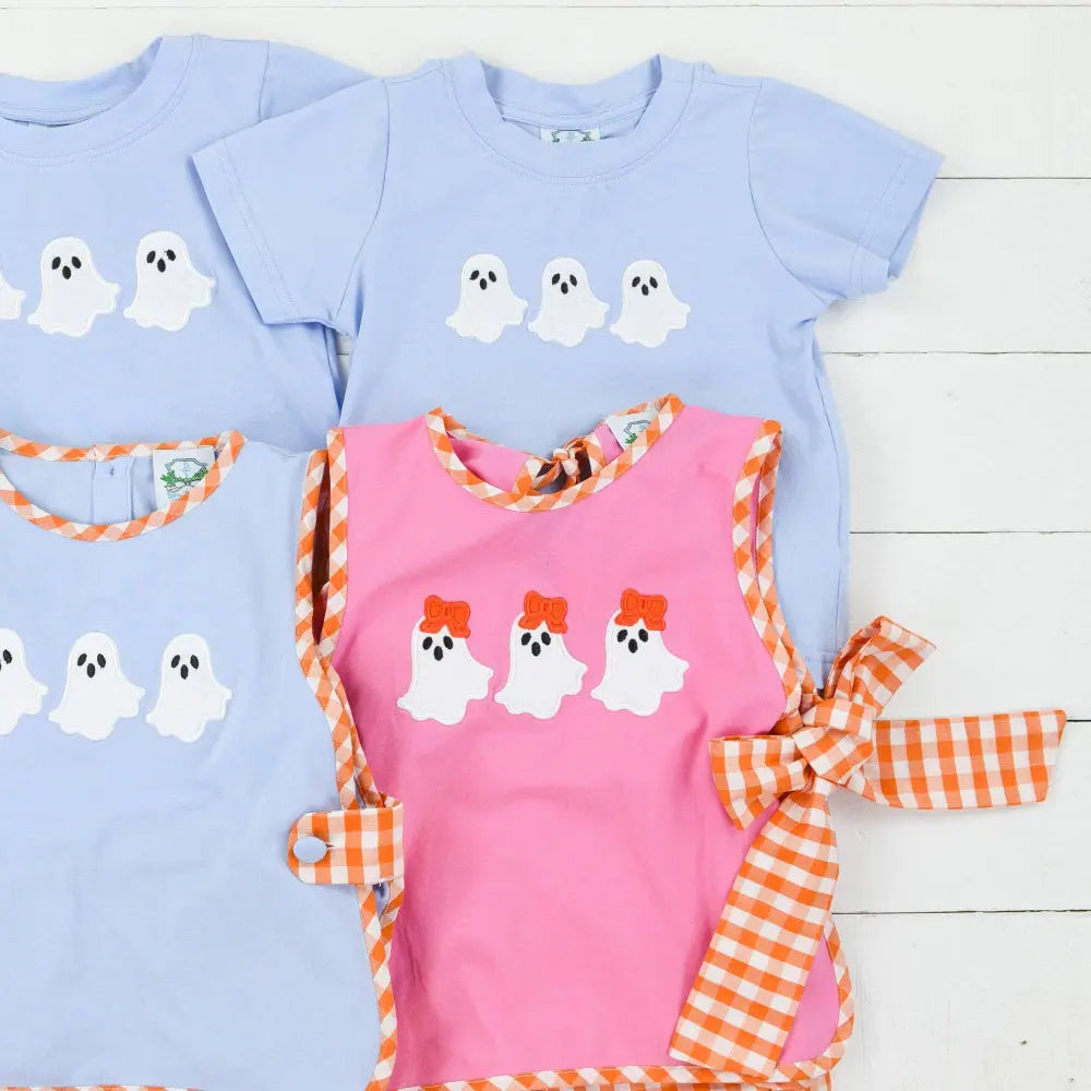 Set of children's shirts with ghost designs on a wooden surface