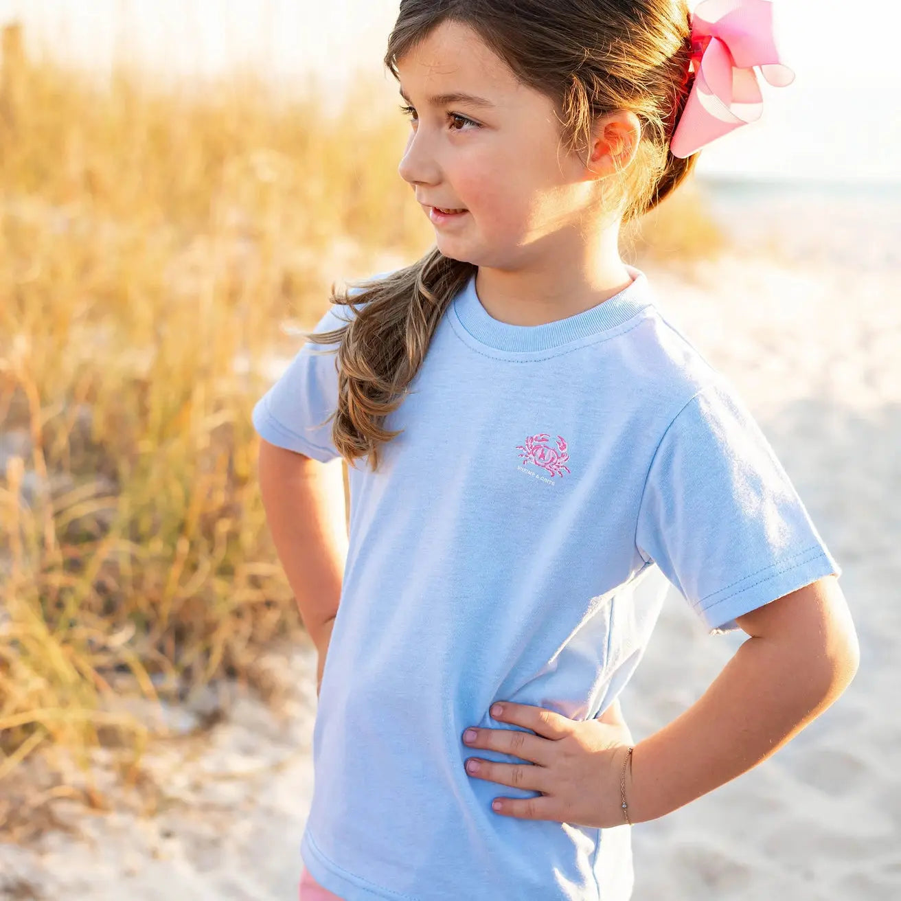 Young girl in a light blue t-shirt with a logo on a beach
