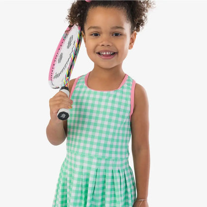 Child in a green checkered dress holding a tennis racket on a white background