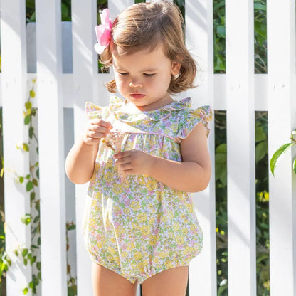Young girl in a floral dress standing in front of a white lattice background