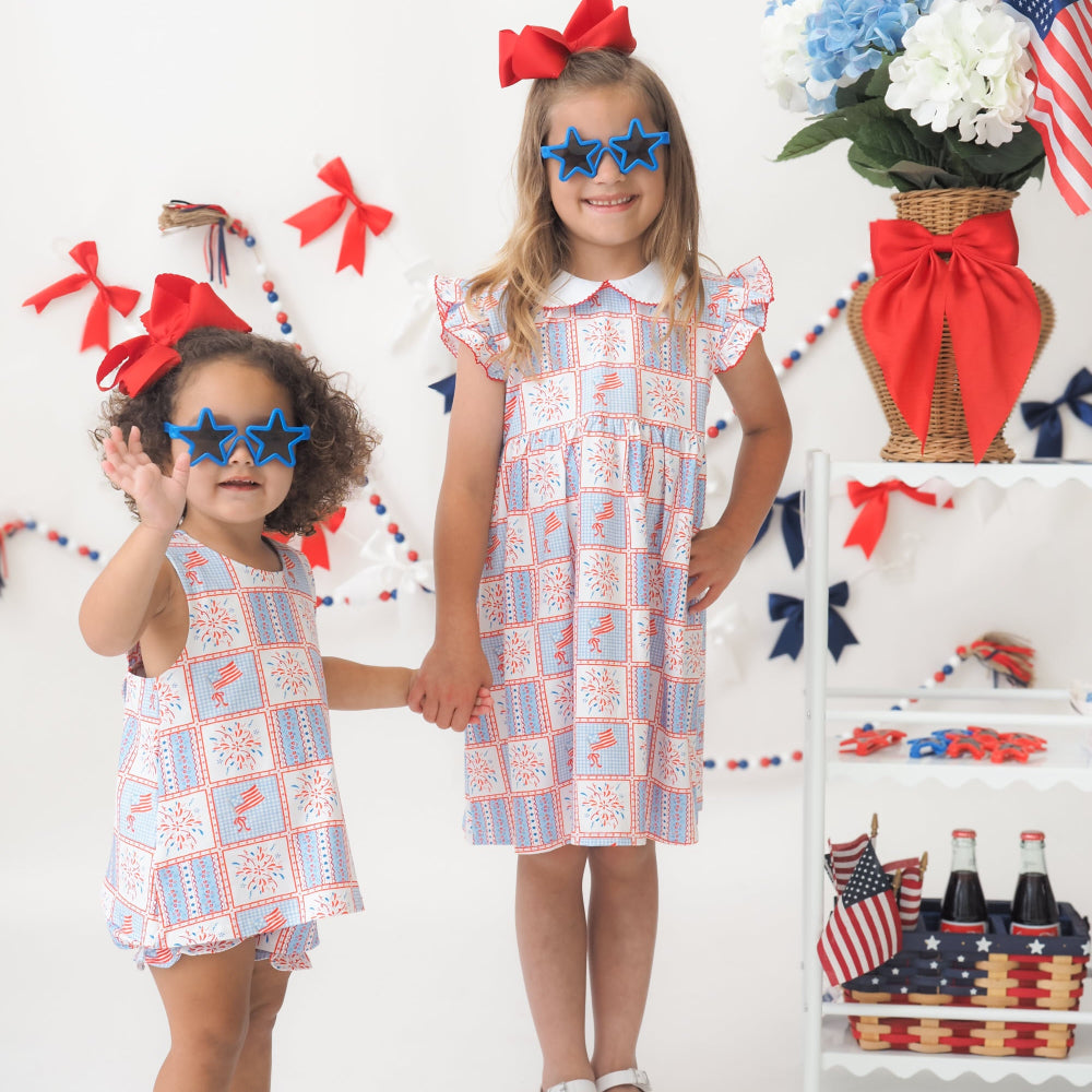 Two young girls in matching dresses with patriotic decorations on a white background