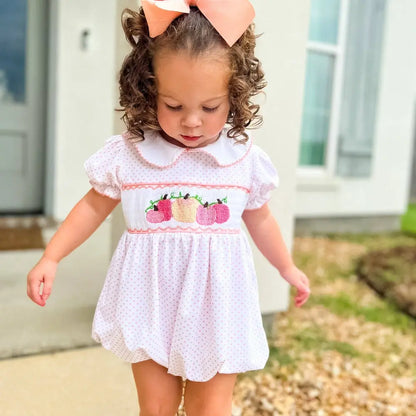 Young girl wearing a white dress with pink accents and a large bow outdoors.