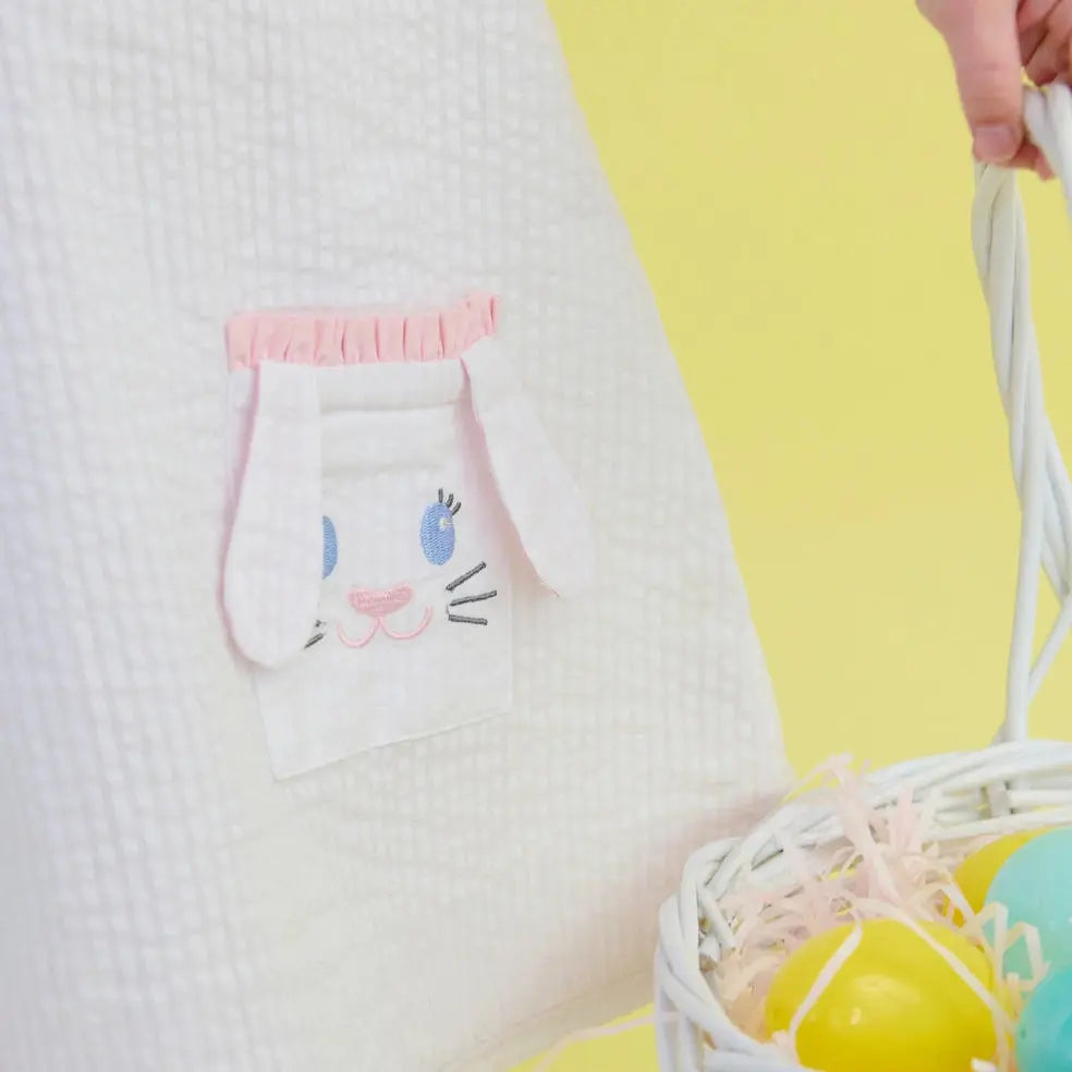 White pillow with cartoon cat face pocket design on a yellow background