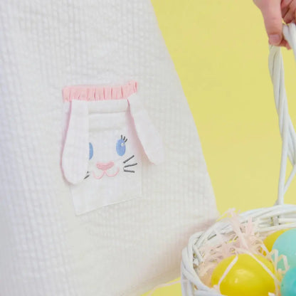 White pillow with cartoon cat face pocket design on a yellow background