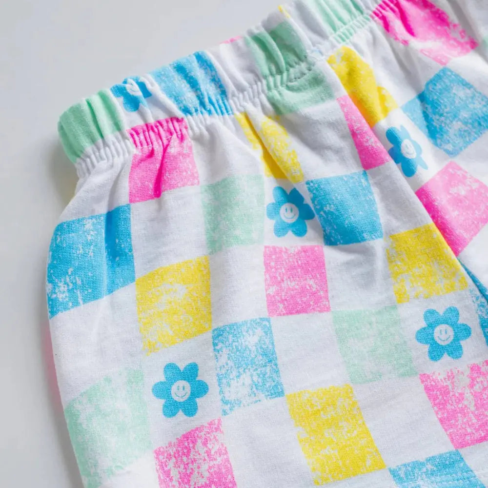 Pair of colorful checkered shorts with floral patterns on a light gray background