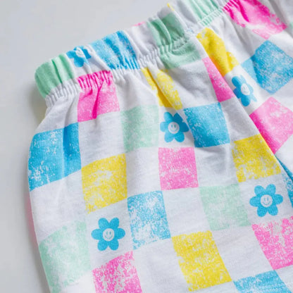 Pair of colorful checkered shorts with floral patterns on a light gray background