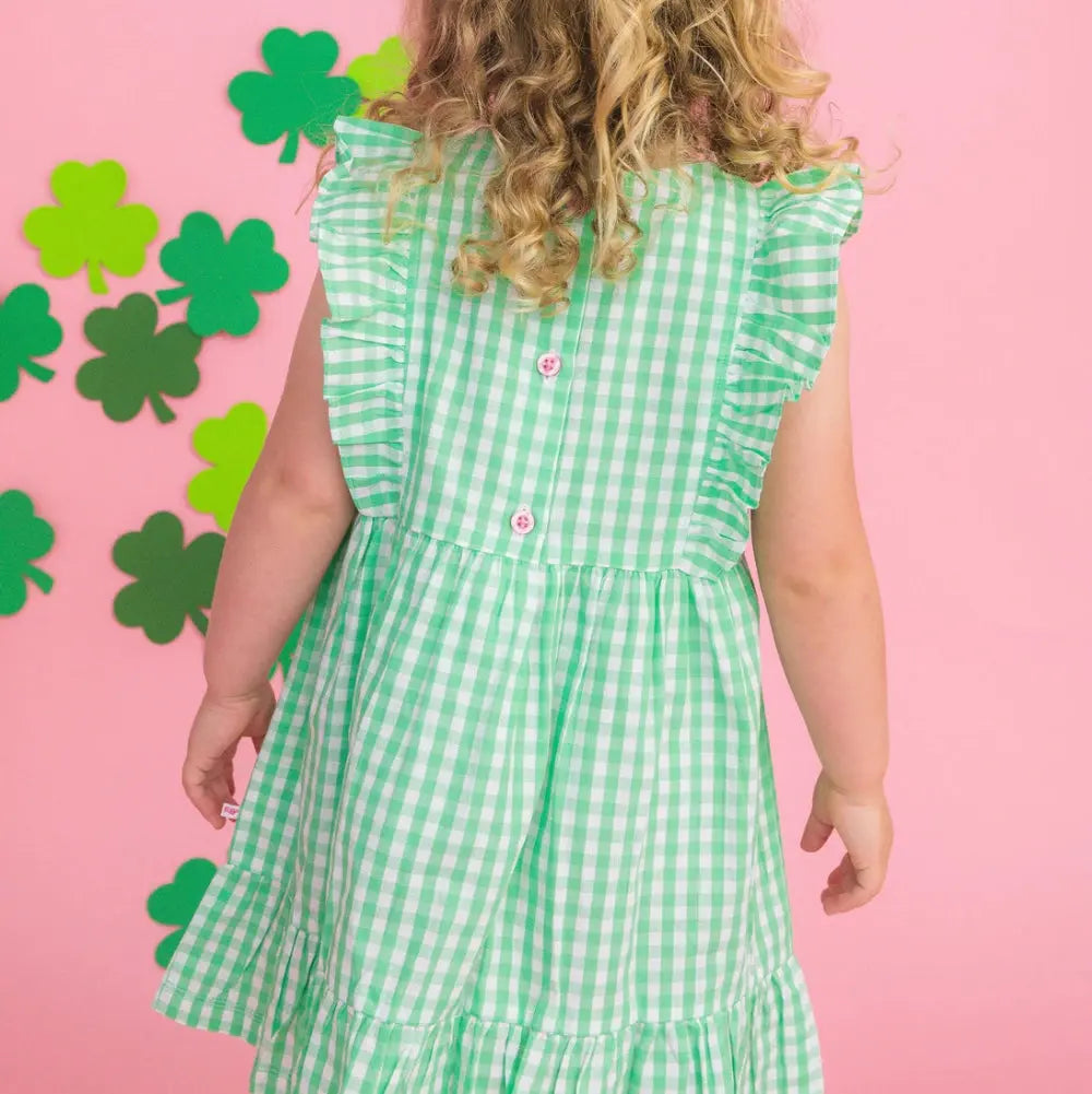 Person wearing a green checkered dress with a pink background and shamrock decorations