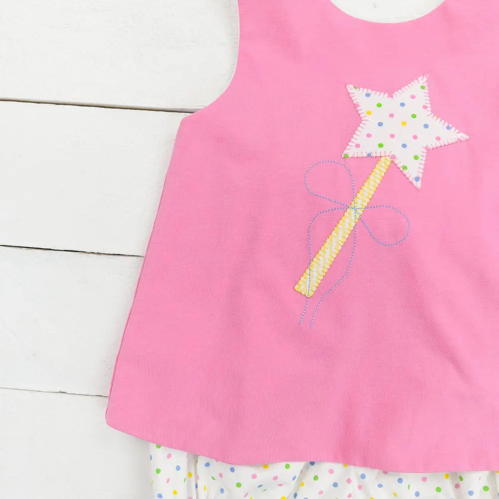 Pink sleeveless top with star wand design on a white wooden surface