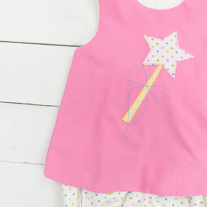 Pink sleeveless top with star wand design on a white wooden surface
